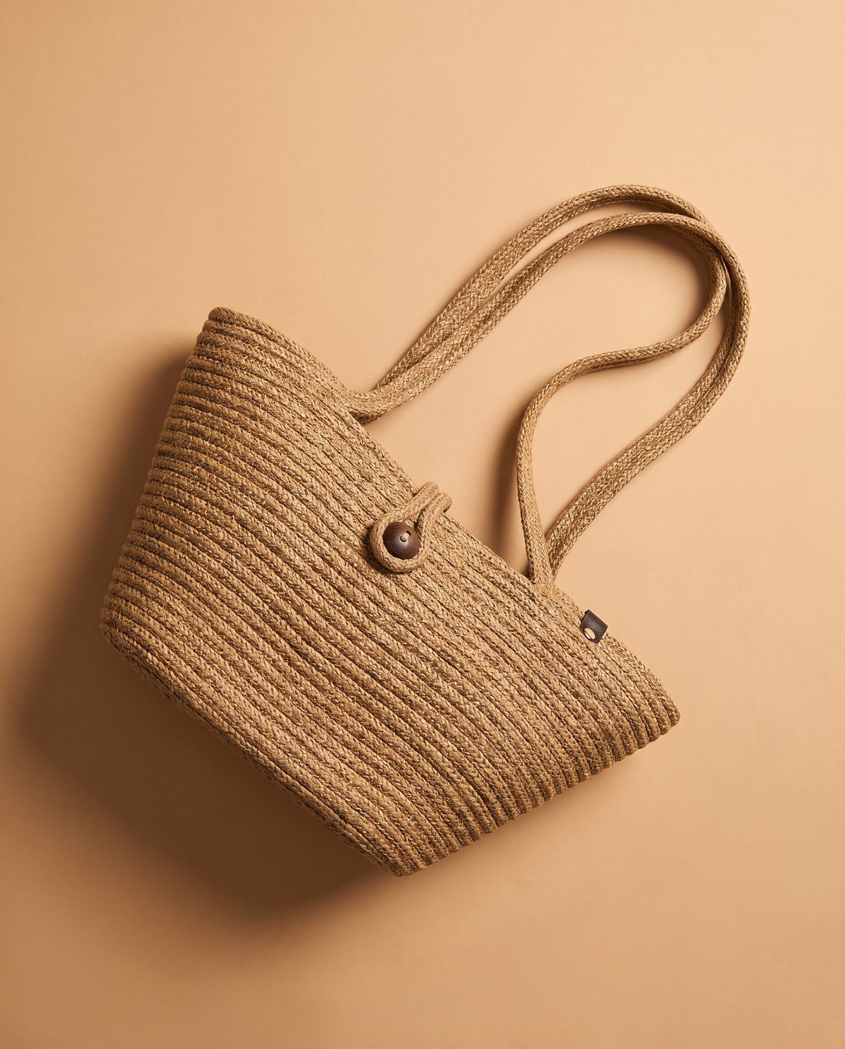 Deneb Buttoned Straw Shoulder Bag in taupe, view 2 angled to show the straps and button closure – Nouva